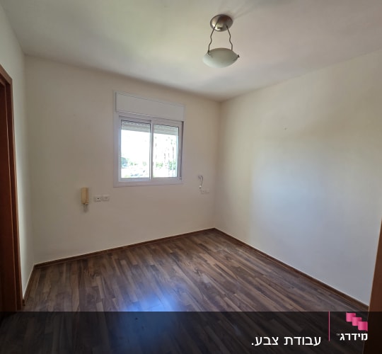 חדר ריק עם רצפת עץ וקירות לבנים